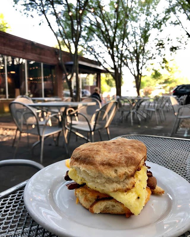 A biscuit on a plate sitting on an outdoor table.